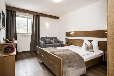 a hotel room with a bed and a chair at Hotel Zum Löwen - Al Leone in Meltina