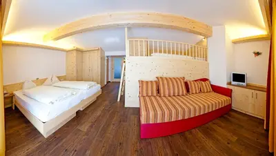 a bedroom with a bunk bed and a couch at Hotel Zum Löwen - Al Leone in Meltina