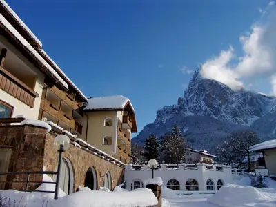 a snow covered building with a mountain in the background at Activehotel Diana in Siusi