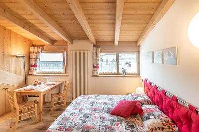 a bedroom with a red bed and a table at Holiday Apartments Val Moena 1 in Cavalese