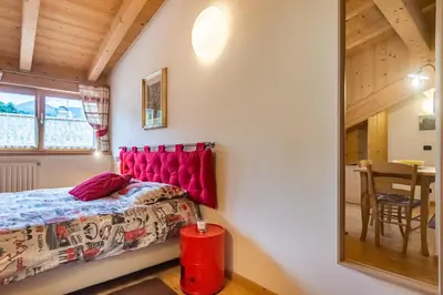 a bedroom with a red headboard and a table at Holiday Apartments Val Moena 1 in Cavalese