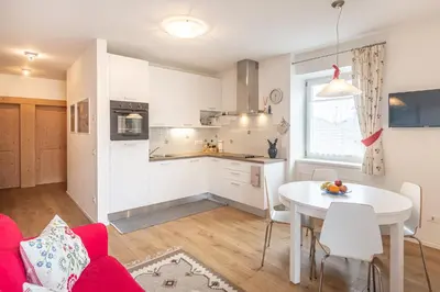 a kitchen and living room with a table and a red couch at Holiday Apartments Val Moena 1 in Cavalese