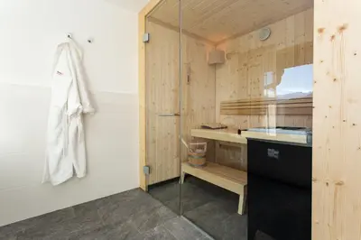 a bathroom with a glass shower and a sink at Granpanorama Hotel StephansHof in Villandro