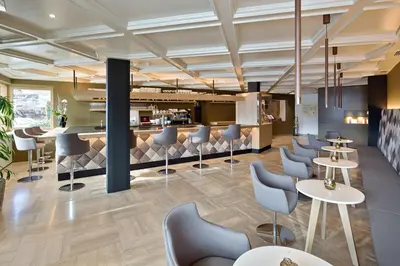 a lobby with tables and chairs and a bar at Granpanorama Hotel StephansHof in Villandro
