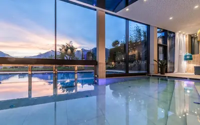 an indoor swimming pool in a house with large windows at Schenna Resort in Schenna