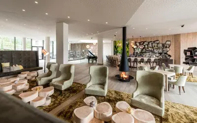 a lobby with chairs and tables and a fireplace at Schenna Resort in Schenna
