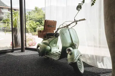 a green scooter parked next to a window at Schenna Resort in Schenna