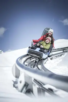 two people riding on a roller coaster in the snow at Schenna Resort in Schenna