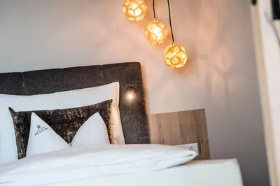 a bedroom with a bed with white sheets and lights at Schenna Resort in Schenna