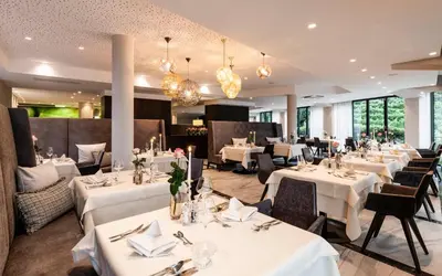 a restaurant with white tables and chairs and chandeliers at Schenna Resort in Schenna