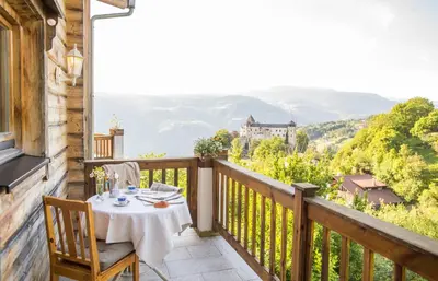 a table on a balcony with a view of a castle at Schlossblick in Vols am Schlern