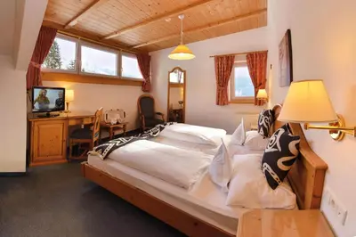 a bedroom with a bed and a desk with a television at The Vista Hotel in Bressanone