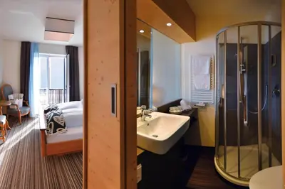 a bathroom with a sink and a shower and a bed at The Vista Hotel in Bressanone