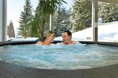 a man and woman sitting in a hot tub at The Vista Hotel in Bressanone