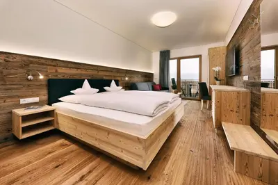 a bedroom with a large bed and a wooden wall at Garni Oberanger in Tirolo