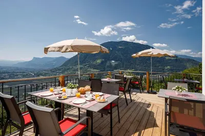 a restaurant with tables and umbrellas on a deck at Garni Oberanger in Tirolo