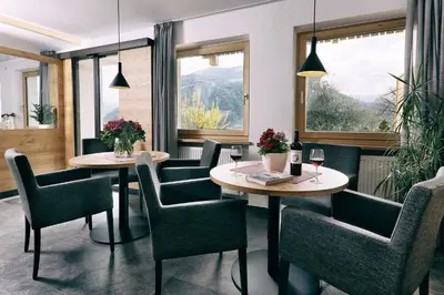 a restaurant with two tables and chairs and windows at Garni Oberanger in Tirolo