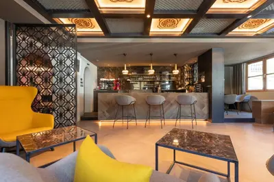 a lobby with a bar with stools and tables at Hotel B&B Pardeller in Nova Levante