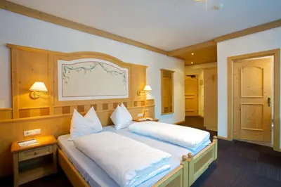 a bedroom with a large bed with white pillows at Hotel B&B Pardeller in Nova Levante