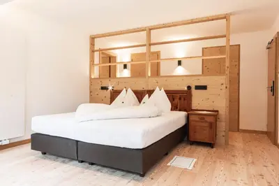 a bedroom with a large bed and a wooden floor at Hotel Tann in Collalbo
