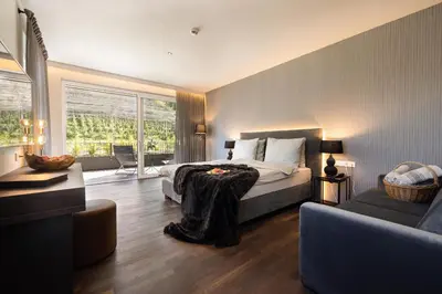 a bedroom with a bed and a living room at Hotel Finkenhof - Feel at home in Schenna