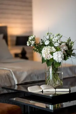 a vase of flowers and a book on a coffee table at Hotel Finkenhof - Feel at home in Schenna