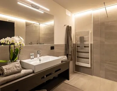 a bathroom with a sink and a large mirror at Hotel Finkenhof - Feel at home in Schenna