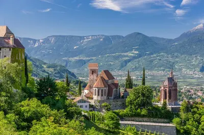 a town on a hill with mountains in the background at Hotel Finkenhof - Feel at home in Schenna