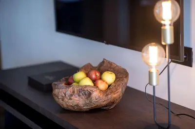 a bowl of fruit sitting on a table next to two lights at Hotel Finkenhof - Feel at home in Schenna