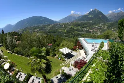 an aerial view of a mansion with mountains in the background at Hotel Finkennest - Panoramic Garden Resort in Schenna