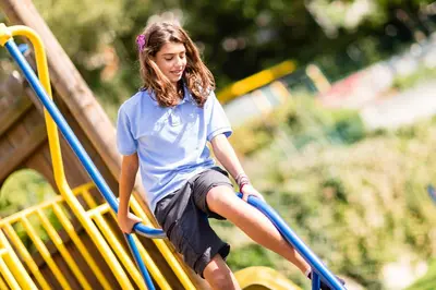 a young girl sitting on a slide at a playground at Hotel Finkennest - Panoramic Garden Resort in Schenna