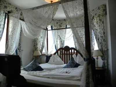 a bedroom with a canopy bed with blue and white curtains at Hotel Finkennest - Panoramic Garden Resort in Schenna
