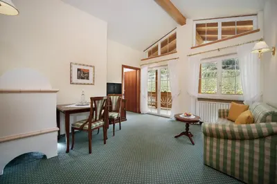 a living room with a couch and a table and a desk at Landhaus Hotel Kristall in Marlengo