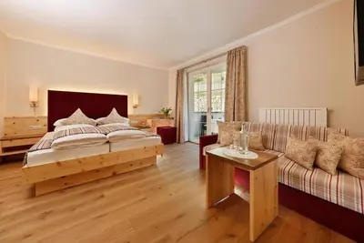 a bedroom with a bed and a couch at Landhaus Hotel Kristall in Marlengo