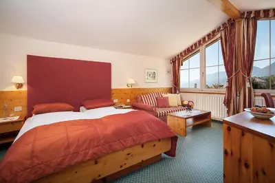 a bedroom with a bed and a couch in a room at Landhaus Hotel Kristall in Marlengo