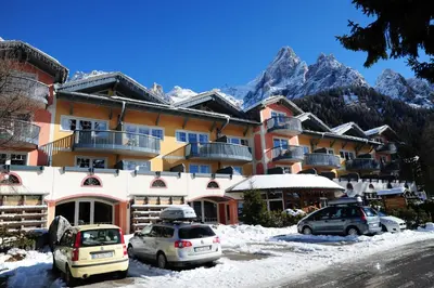 a large building with cars parked in the snow at Sporting Aparthotel in San Martino di Castrozza