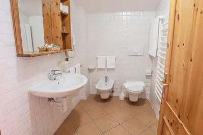 a white bathroom with a sink and a toilet at Sporting Aparthotel in San Martino di Castrozza