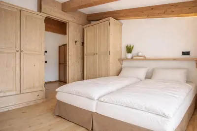 a large white bed in a room with wooden walls at Sporting Aparthotel in San Martino di Castrozza