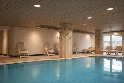a pool in a room with chairs at Sporting Aparthotel in San Martino di Castrozza