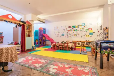 a room with a dining table and a playroom with a table and chairs at Sporting Aparthotel in San Martino di Castrozza