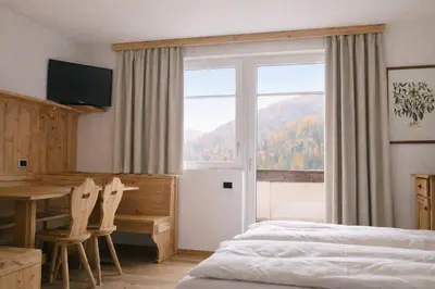 a bedroom with a bed and a desk and a window at Sporting Aparthotel in San Martino di Castrozza