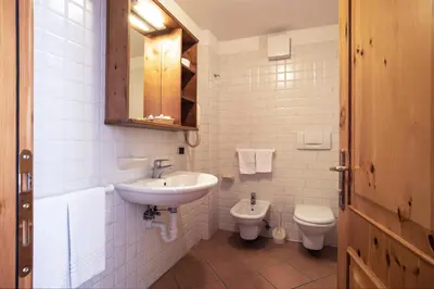 a white bathroom with a sink and a toilet at Sporting Aparthotel in San Martino di Castrozza