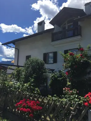 a white house with red flowers and a fence at Lochererhof in Appiano sulla Strada del Vino