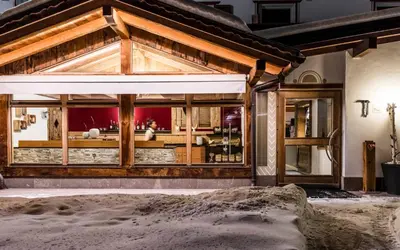 a building with a large window with snow on the ground at Rainell Dolomites Retreat in Ortisei