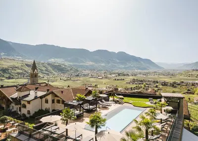 a resort with a pool and a church at Hotel Kassian in Lagundo