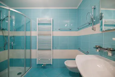 a blue tiled bathroom with a toilet and a sink at PLAN DE CORONES apartments in San Vigilio Di Marebbe