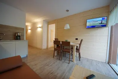 a dining room with a table and a tv on a wall at PLAN DE CORONES apartments in San Vigilio Di Marebbe