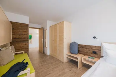 a bedroom with a bed and a wooden wall at PLAN DE CORONES apartments in San Vigilio Di Marebbe