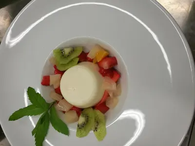 a white bowl with fruit and ice cream on a plate at Residence Terentis in Terento