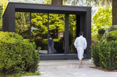 a woman in a white suit looking at a statue at Villa Eden a member of Leading Hotels of the World in Merano